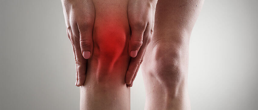 A person holding their knee with the red area showing.
